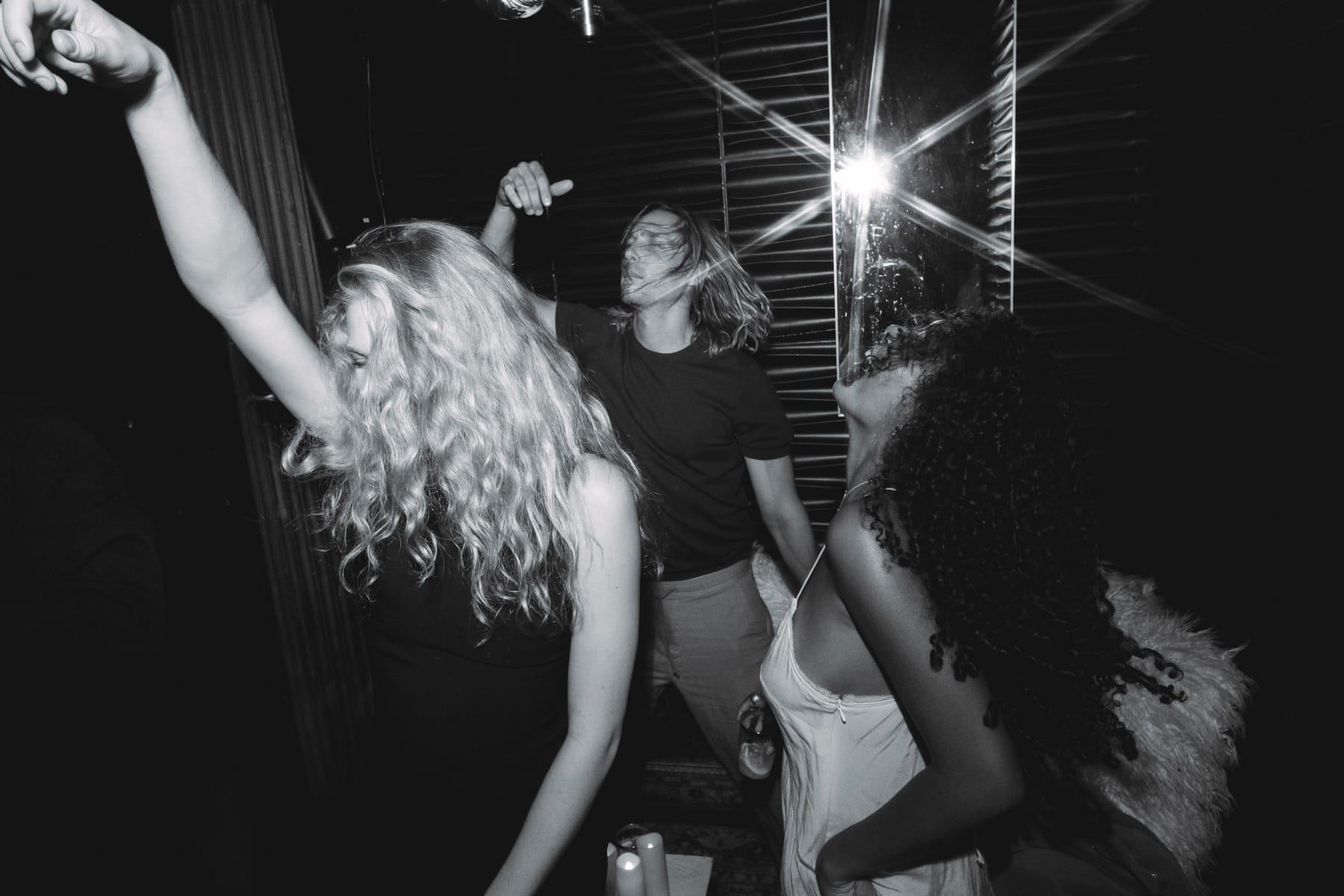 Dancers mid-move, hair flying, with a starburst of light behind them.